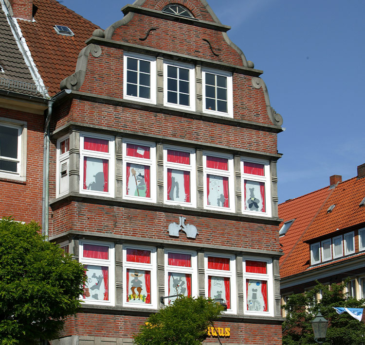 Außenansicht eines Backsteinhauses mit bemalten Fenstern.