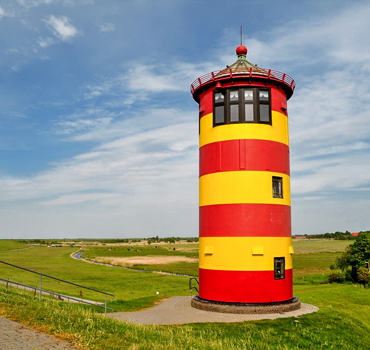Nahaufnahme eines rot-gelb gestreiften Leuchtturms auf einer Wiese.