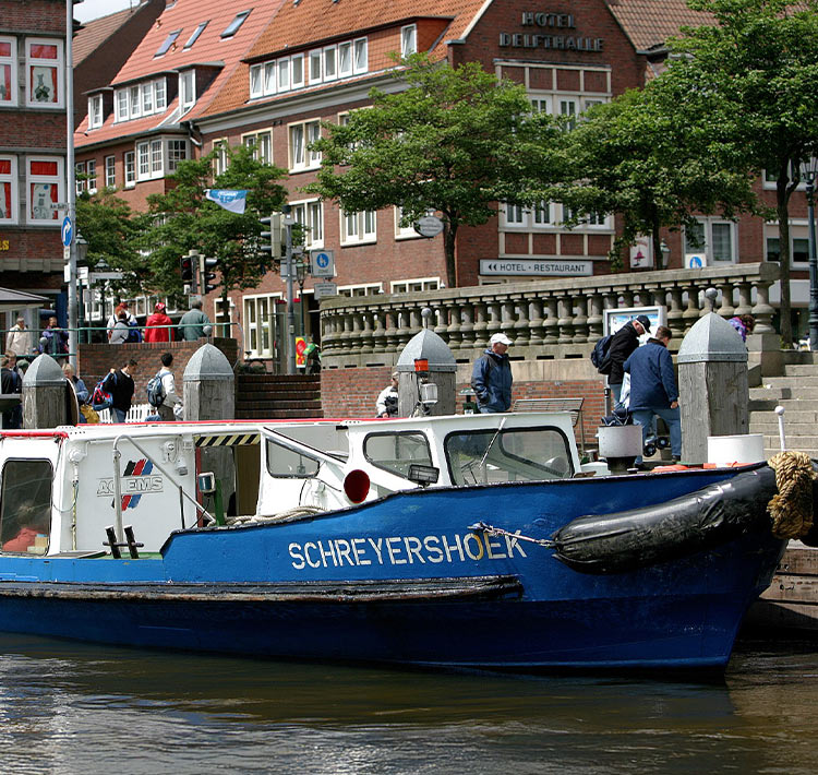 Nahaufnahme eines Bootes vor Backsteinhäusern.