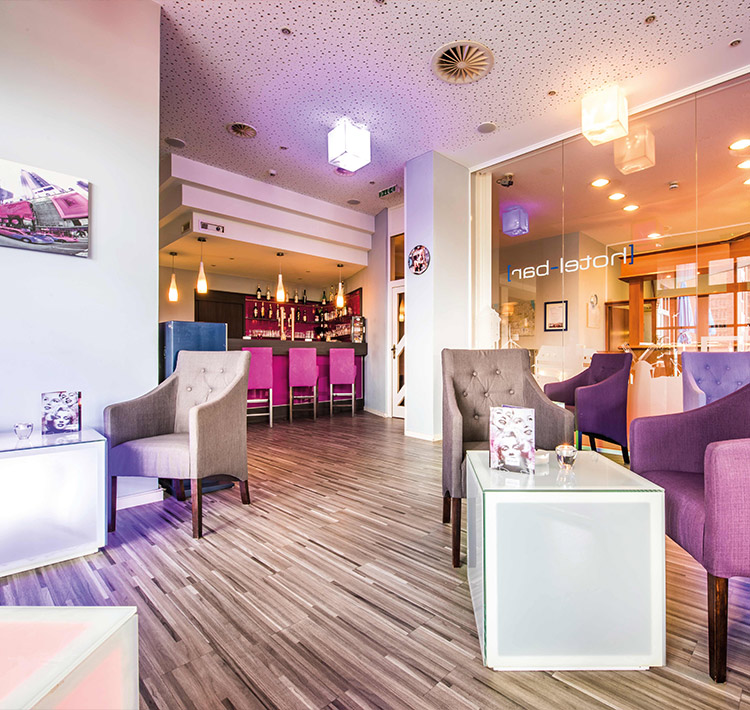 Moderne Lounge mit Sesseln, Leuchtwürfel-Tischen und Leuchtwürfel-Deckenlampen.