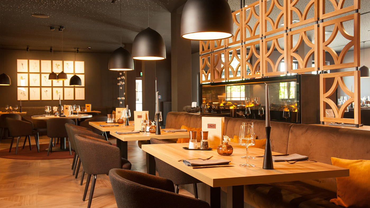 Restaurant mit eingedeckten Tischen und einer Feuerstelle.
