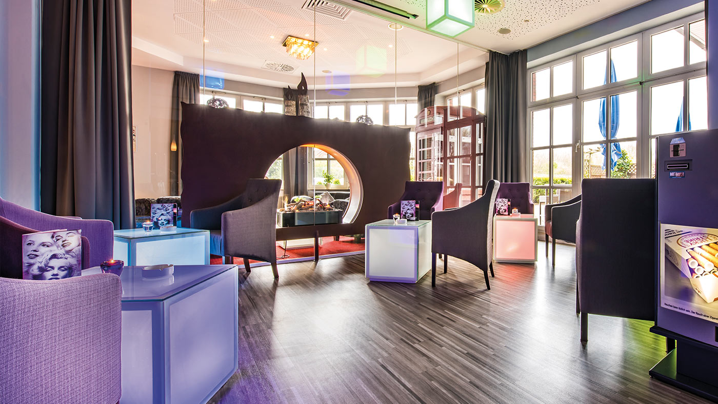 Moderne Lounge mit Sesseln, Leuchtwürfel-Tischen und Leuchtwürfel-Deckenlampen.