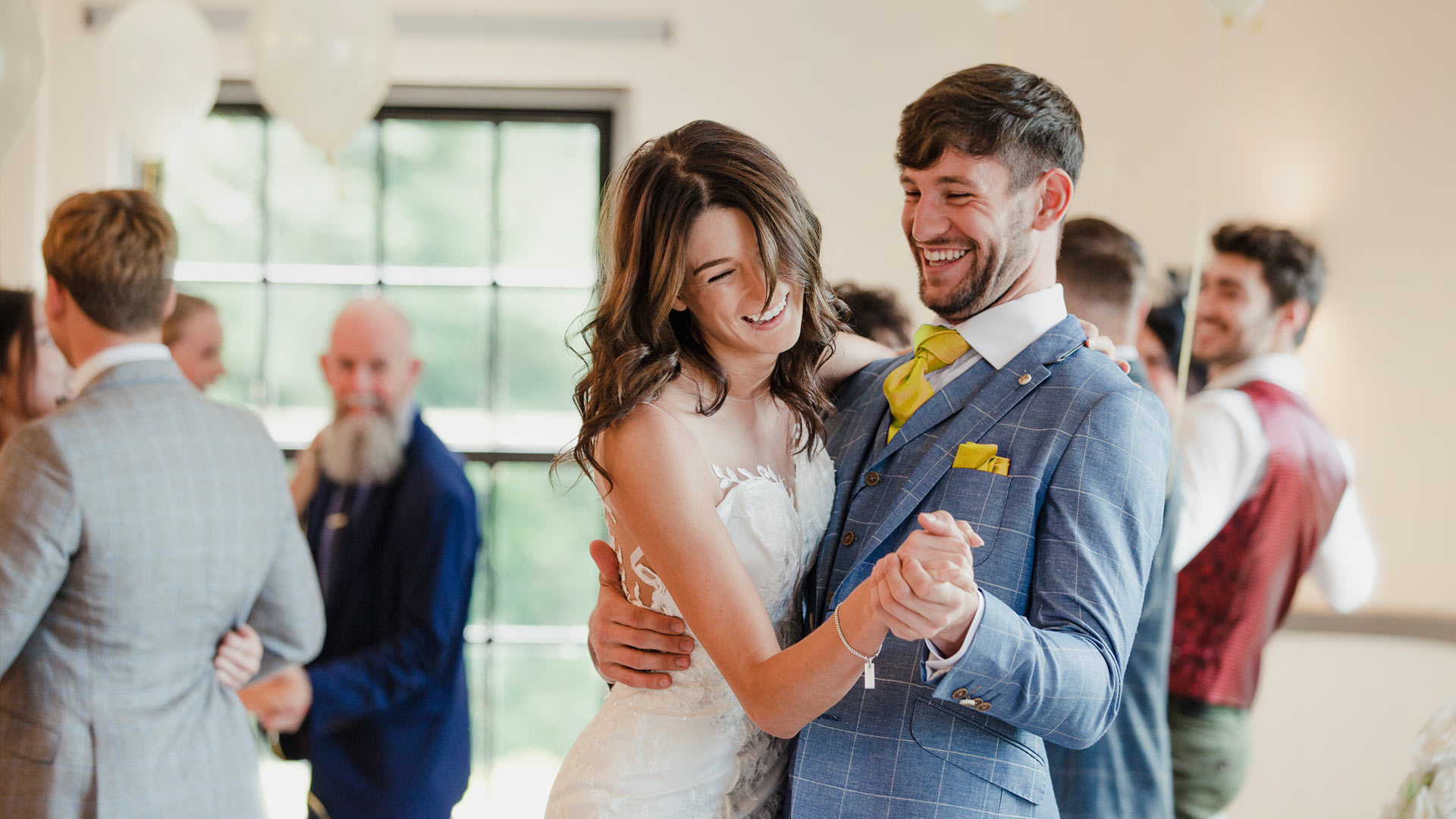 Hochzeitspaar tanzt mit Gästen im Hintergrund