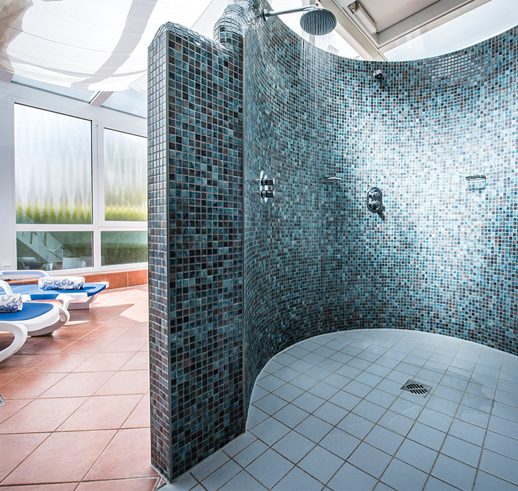 Nahaufnahme einer Dusche mit blau-schwarzen Fliesen.