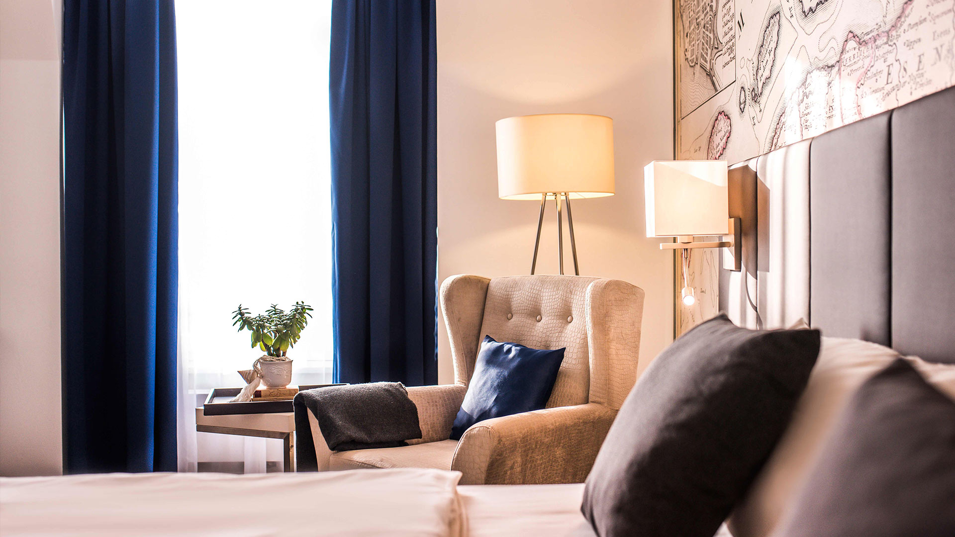 Aufnahme eines Hotelzimmers mit Sessel, Lampe und Wandbild.