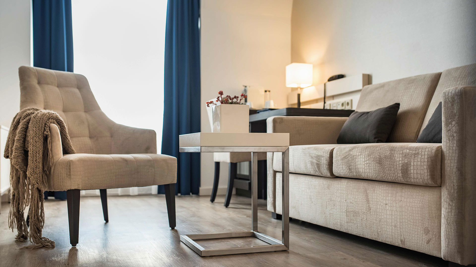 Nahaufnahme eines Sofatisches mit einem Blumentopf, zwischen einem Sofa und einem Sessel.