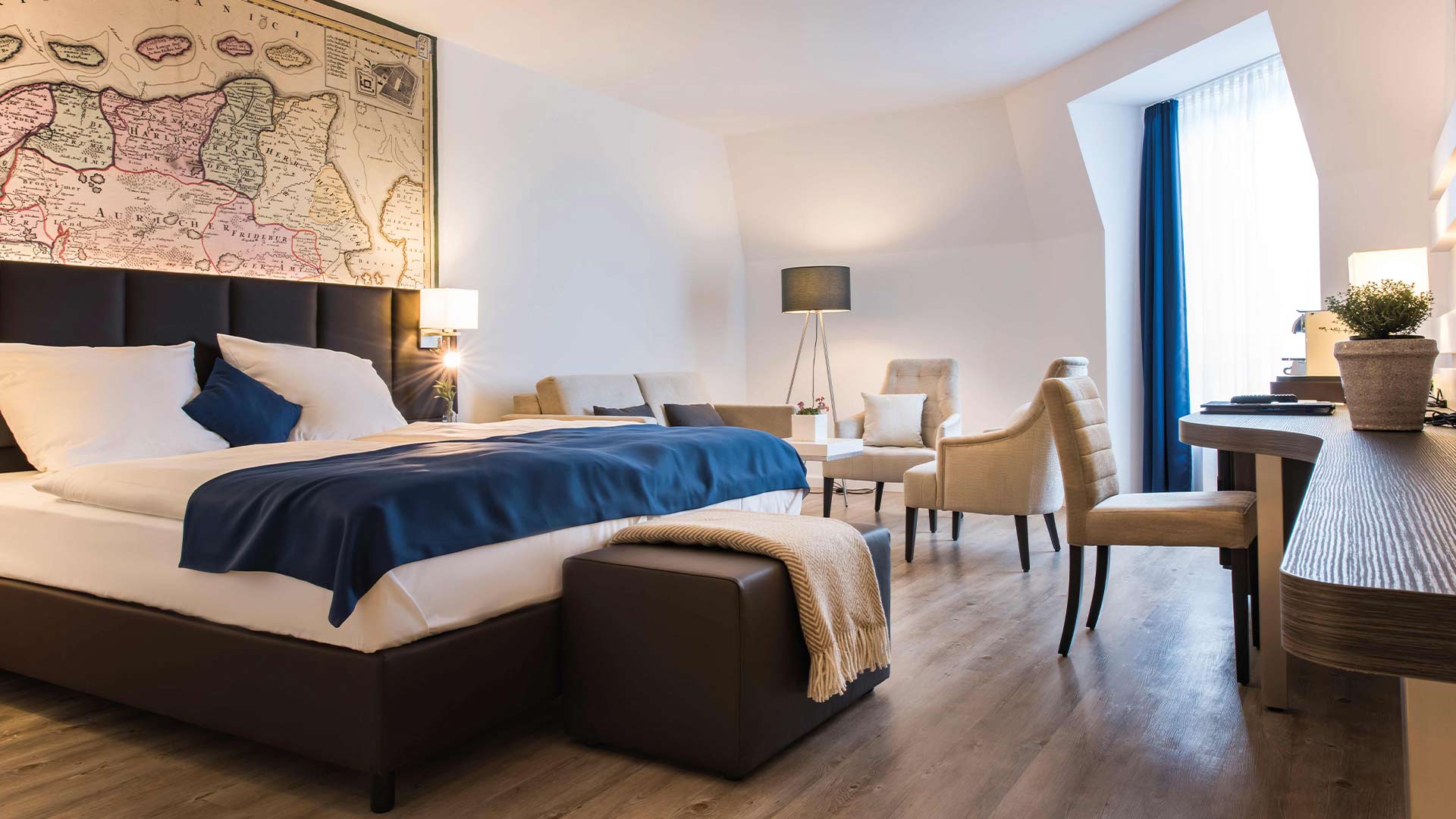 Hotelzimmer mit Bett, Sofa und Wandbild.