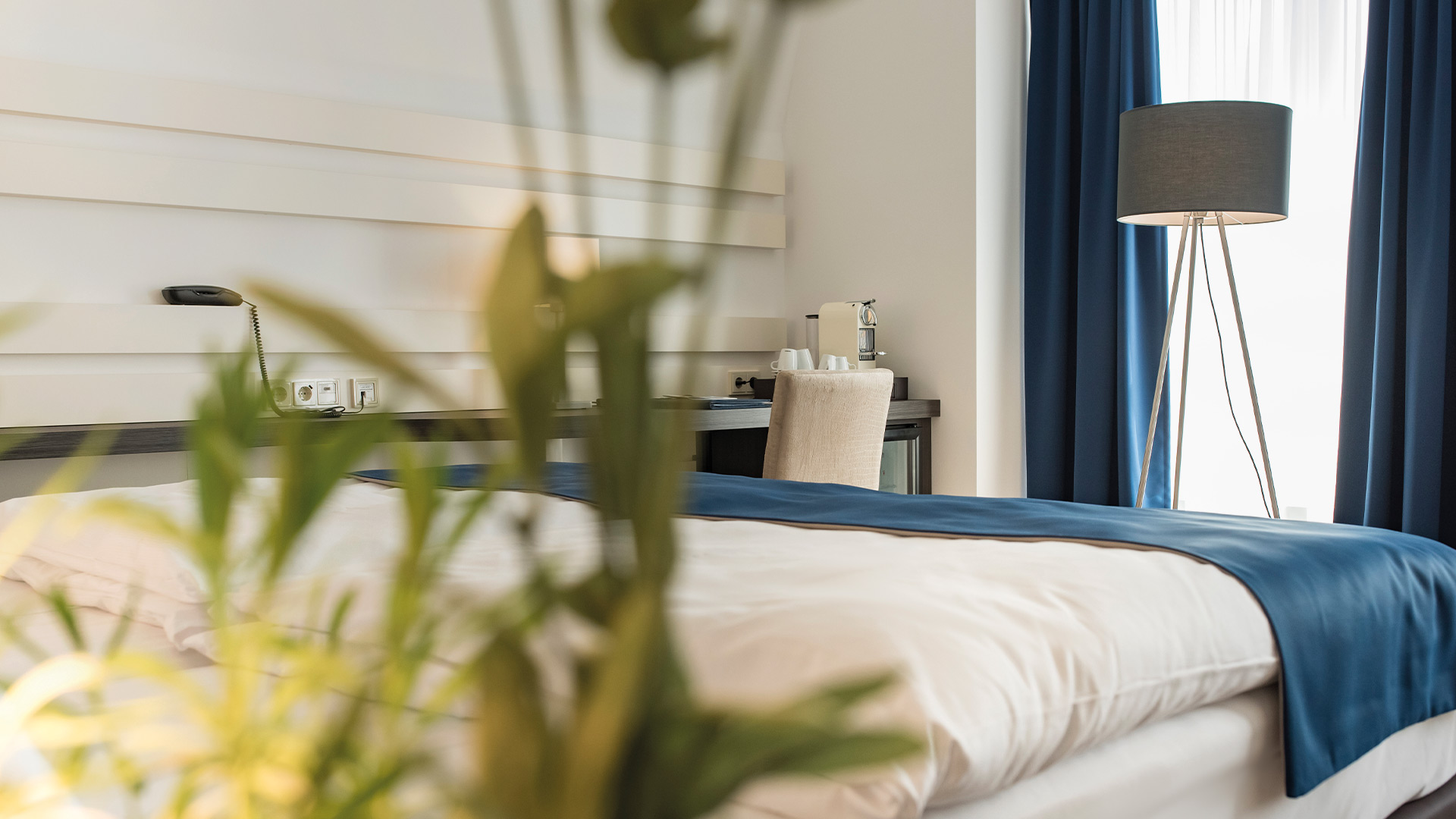 Nahaufnahme eines Bettes und einer Pflanze in einem Hotelzimmer.