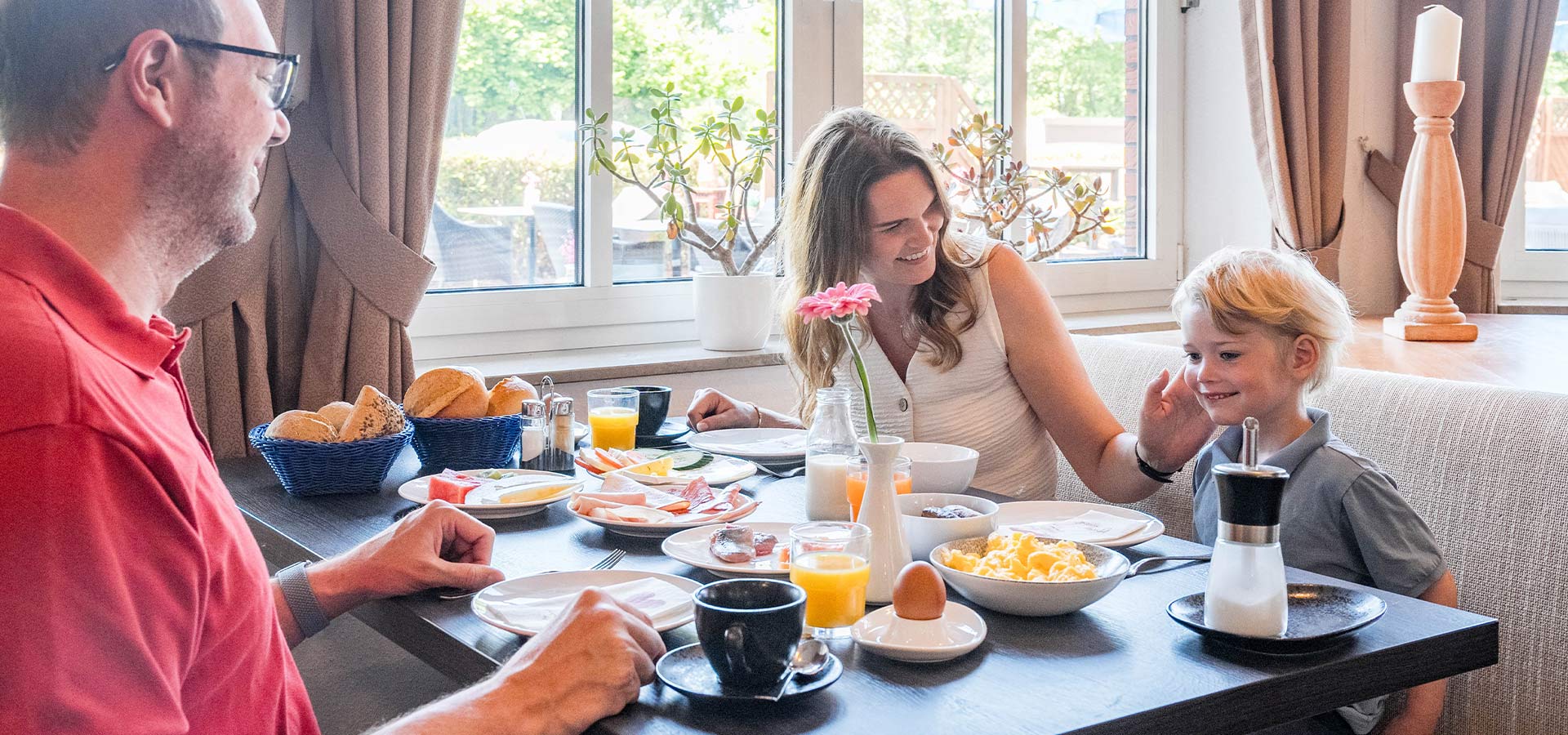 Familie beim Frühstück an einem gedeckten Tisch
