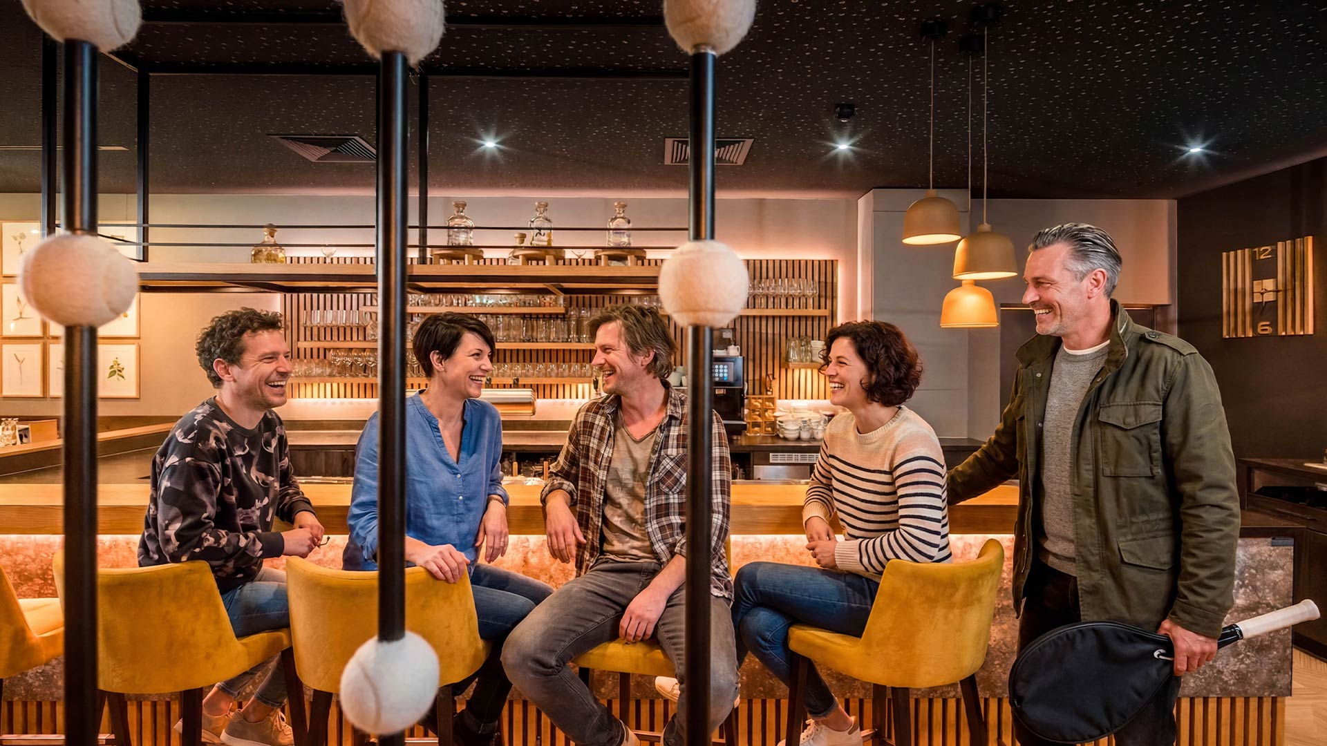 Gruppe Menschen sitzt lachend an einer Bar-Theke
