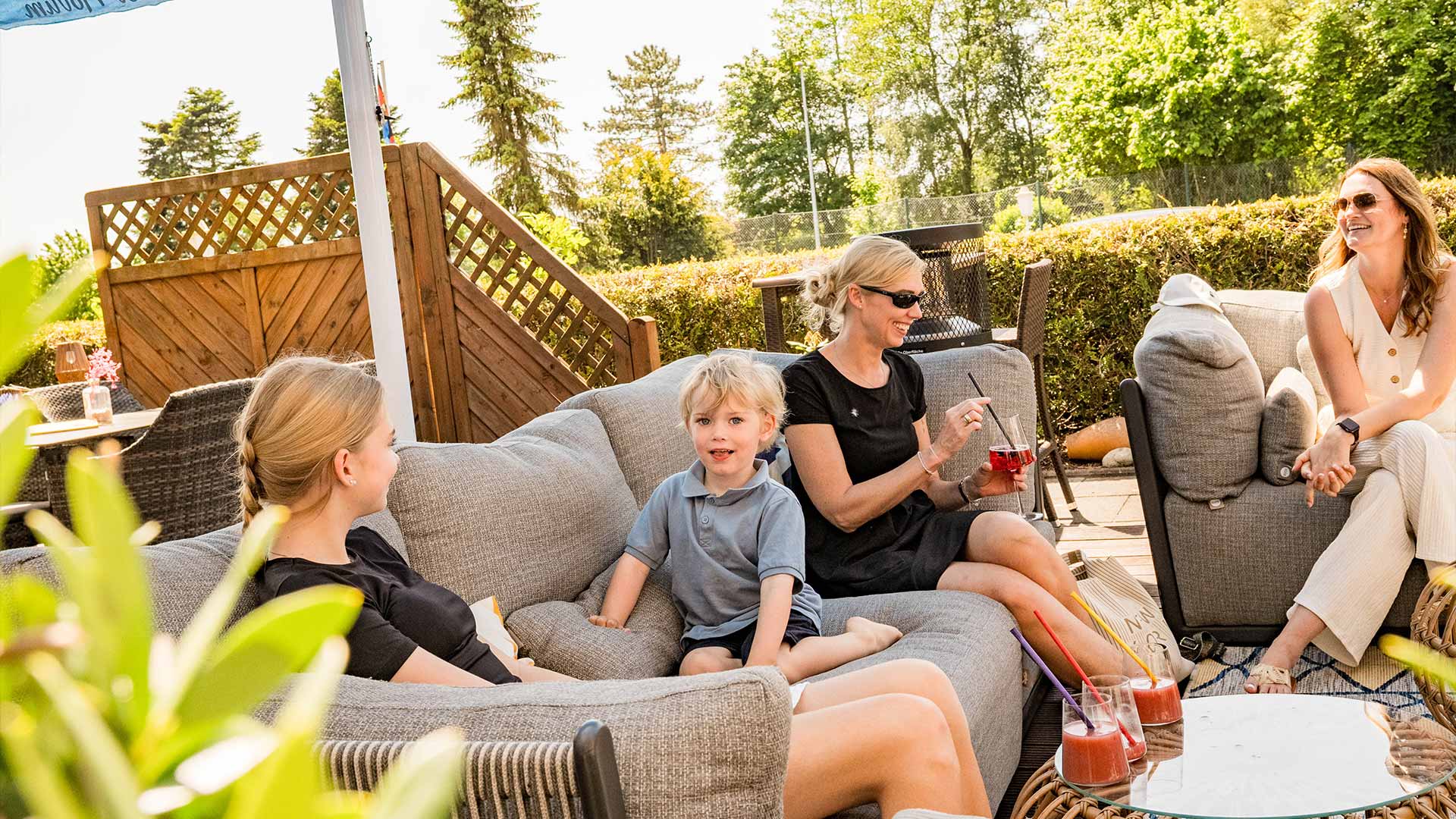 Frauen und Kinder sitzen auf Sofas in der Sonne